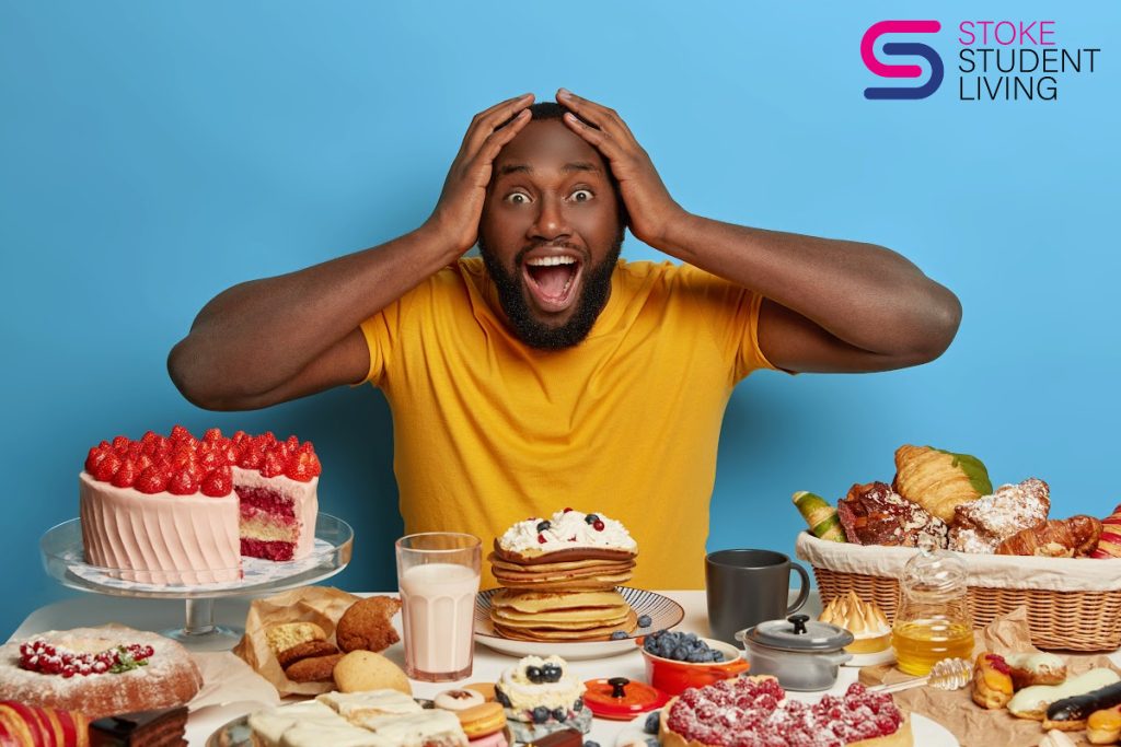 A man with a delighted and surprised look on his face is in front of a table laddened with all sorts of delish food.