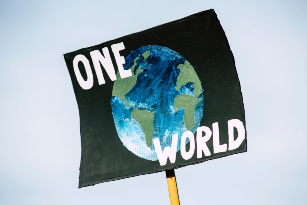 Banner held aloft with a picture of the Earth on a black background and the words 'One World'