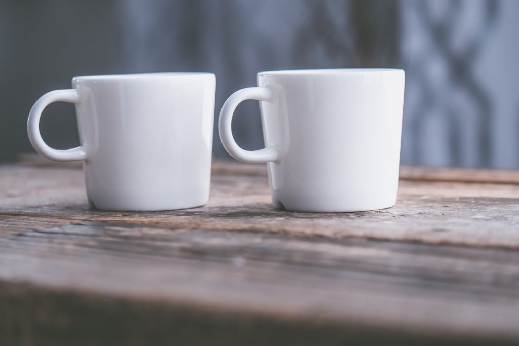 Image of two white coffee cups on a wooden surface