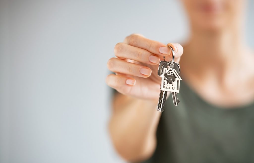 A young person is holding a set of keys close up to the camera. The focus is on the hand and the keys and the person is blurred out.