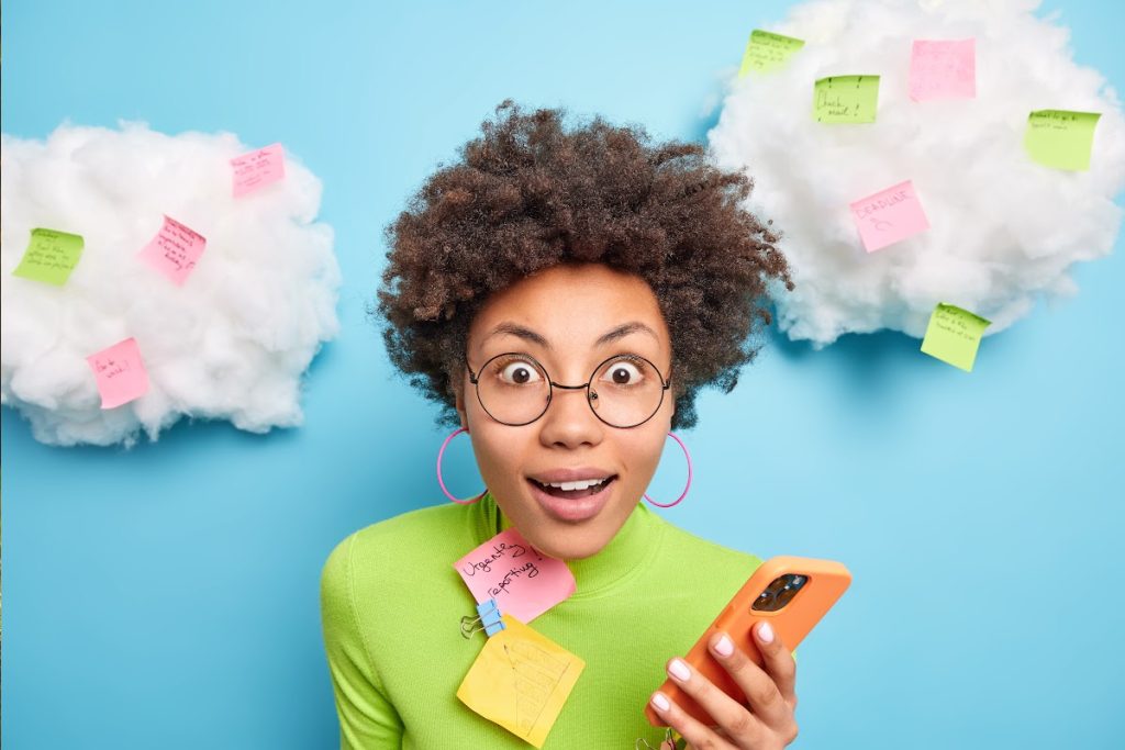 A young woman is holding a phone, around her are 'clouds' and on the clouds are post it notes with text on.